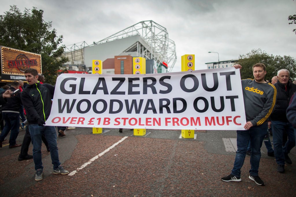 MANCHESTER, ENGLAND - OCTOBER 20: A pair of Man Utd fans hold up a banner against the club's owners, the Glazers, as well as Man Utd Chief Executive Ed Woodward before the Premier League match between Manchester United and Liverpool FC at Old Trafford on October 20, 2019 in Manchester, United Kingdom. Glazer. Protest. United. 