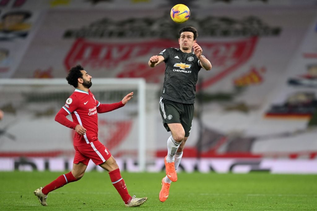 Manchester United's English defender Harry Maguire (C) jumps to head the ball as Liverpool's Egyptian midfielder Mohamed Salah (L) closes in during the English Premier League football match between Liverpool and Manchester United at Anfield in Liverpool, north west England on January 17, 2021. (Photo by Michael Regan / POOL / AFP) / RESTRICTED TO EDITORIAL USE. No use with unauthorized audio, video, data, fixture lists, club/league logos or 'live' services. Online in-match use limited to 120 images. An additional 40 images may be used in extra time. No video emulation. Social media in-match use limited to 120 images. An additional 40 images may be used in extra time. No use in betting publications, games or single club/league/player publications. /  