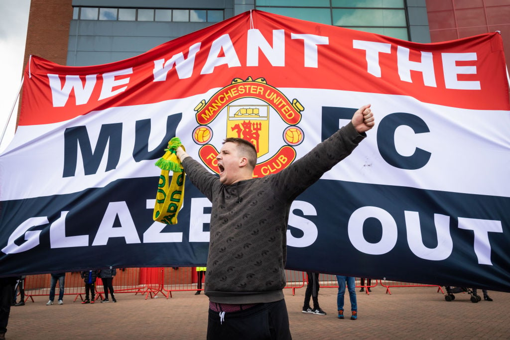 A football fan chants slogans in front of a banner before a