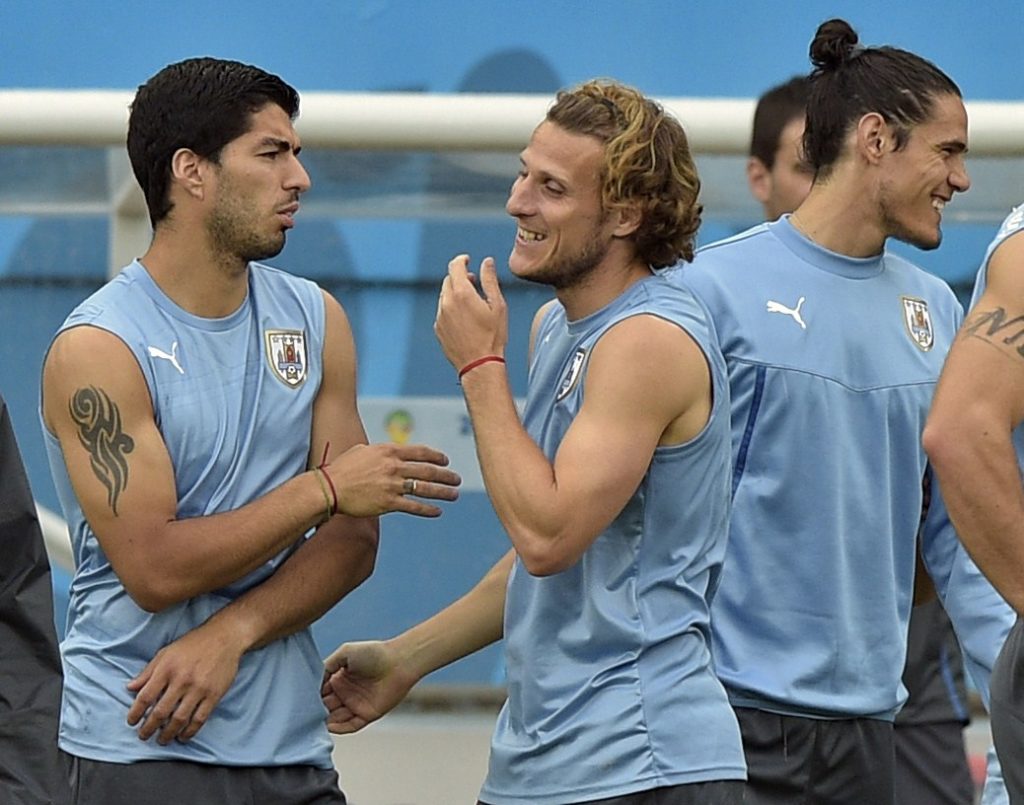 Uruguay's forward Diego Forlan (C) jokes with forward Luis Suarez (L) while forward Edinson Cavani passes by during a training session at  Dunas Ar...