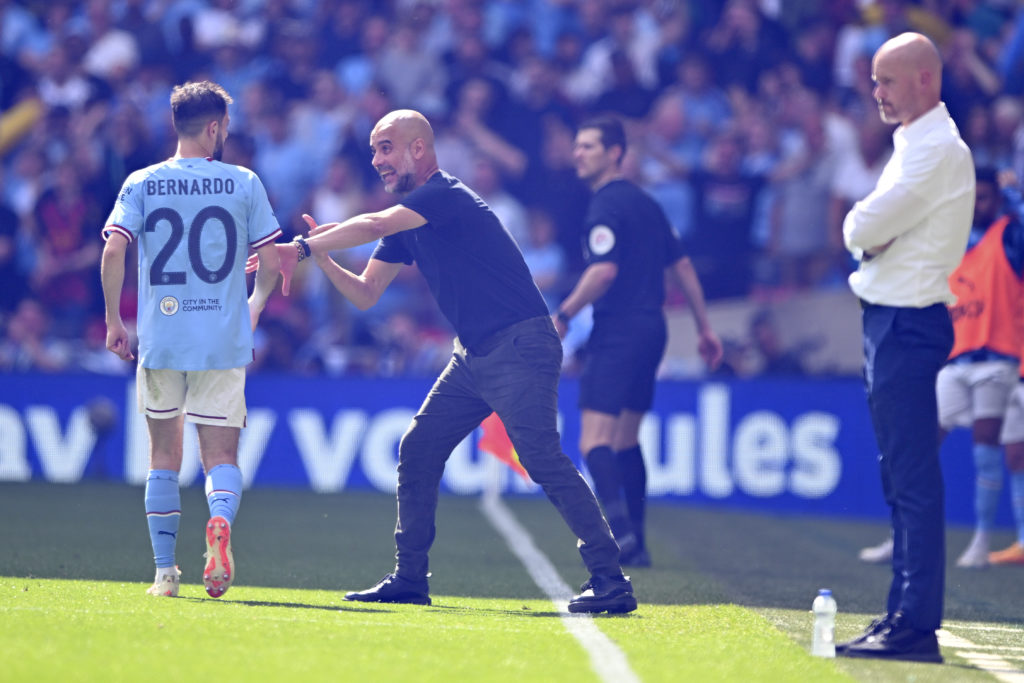 Pep Guardiola, Manager of Manchester City leaves the technical room to speak with Bernardo Silva of Manchester City with Erik ten Hag, Manager of Manchester...