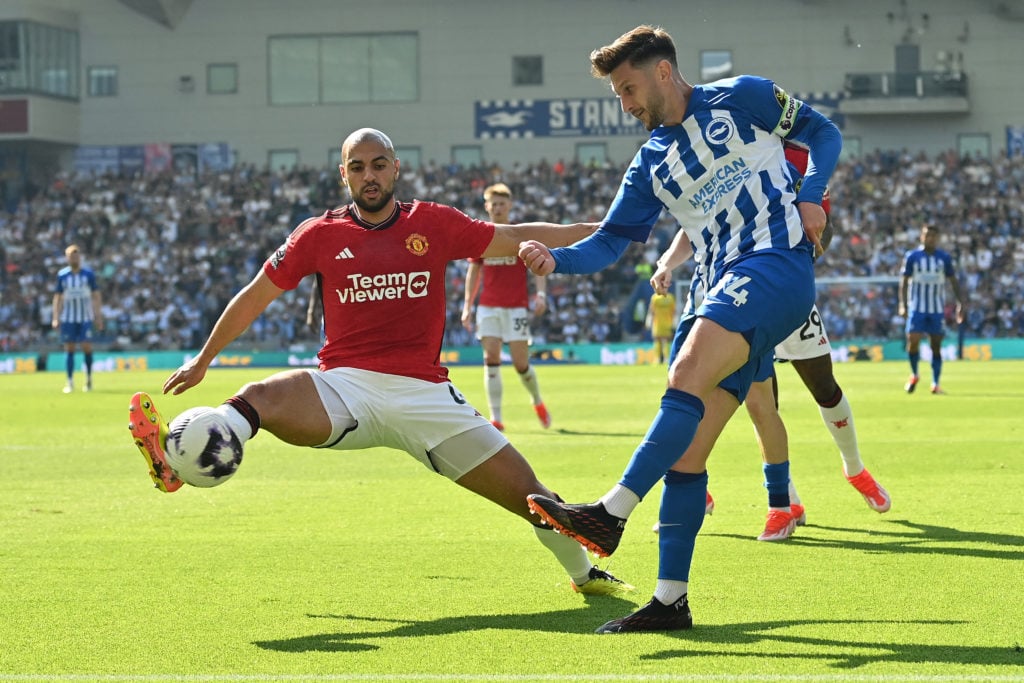 Manchester United's Moroccan midfielder #04 Sofyan Amrabat (L) defends a cross from Brighton's English midfielder #14 Adam Lallana during the Engli...