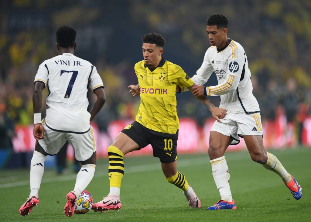 Jadon Sancho of Borussia Dortmund is challenged by Jude Bellingham and Vinicius Junior of Real Madrid during the UEFA Champions League 2023/24 Fin...