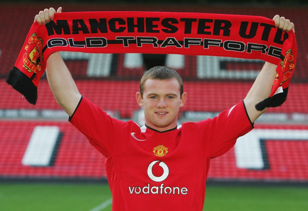 Wayne Rooney poses for photographs with a Manchester United scarf after signing for Manchester United on August 31, 2004 at Old Trafford in Manches...