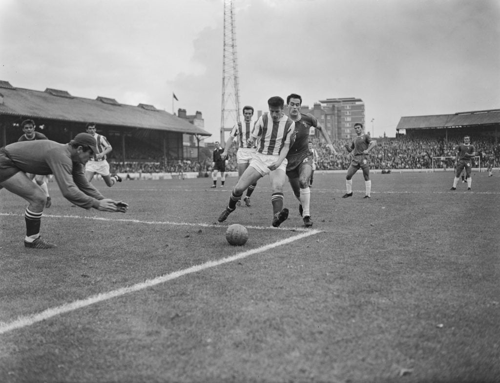 British goalkeeper Peter Bonetti (1941-2020), in goal for Chelsea, dives low to stop the attack from British footballer Dennis Viollet (1933-1999) ...