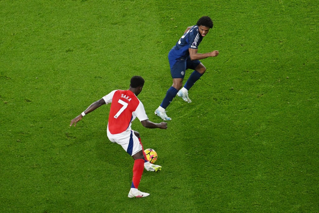 Bukayo Saka of Arsenal runs with the ball under pressure from Tyrell Malacia of Manchester United during the Premier League match between Arsenal F...