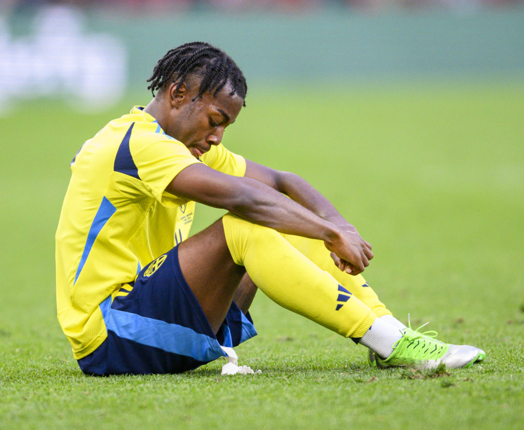 Former Manchester United player Anthony Elanga sits on the pitch in a Sweden kit.