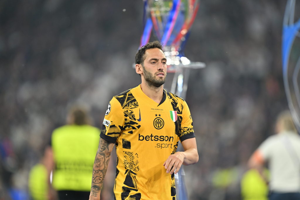 Hakan Calhanoglu walks by the Champions League trophy.