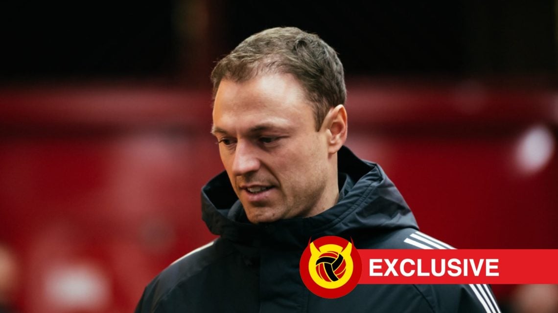 Jonny Evans looking toward the ground in Manchester United jacket. Overlaid UIF logo and exclusive banner.