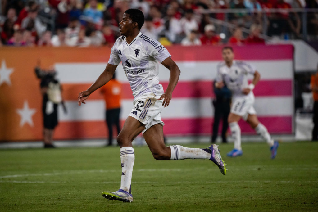 Chido Obi running in white Manchester United kit.