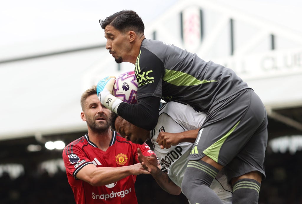 Altay Bayindir catches ball ahead of Fulham player for Manchester United.