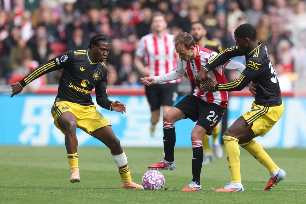 Mikkel Damsgaard of Brentford is put under pressure by Patrick Dorgu (L) and Kobbie Mainoo of Manchester United (R) during the Premier League match between Brentford and Manchester United at Brentford Community Stadium on September 27, 2025