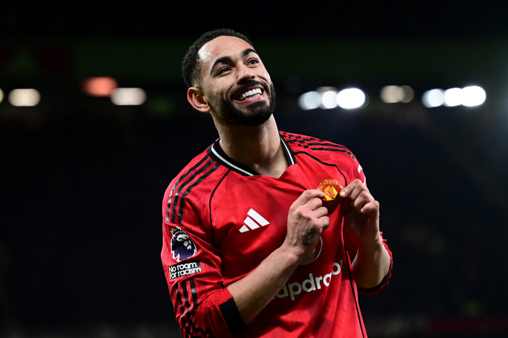 Matheus Cunha holds Manchester United badge.