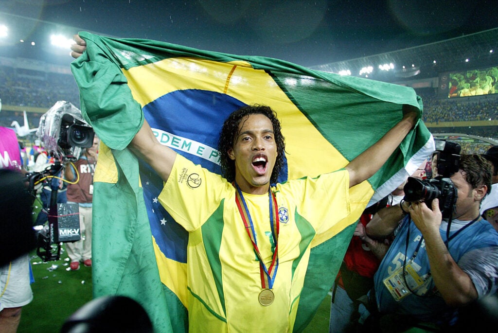 Ronaldinho do Brasil usando medalha comemora com Copa do Mundo e bandeira